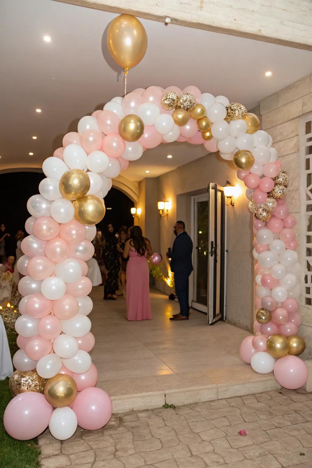 A beautiful balloon arch in pink, gold, and white cheerfully greets guests.