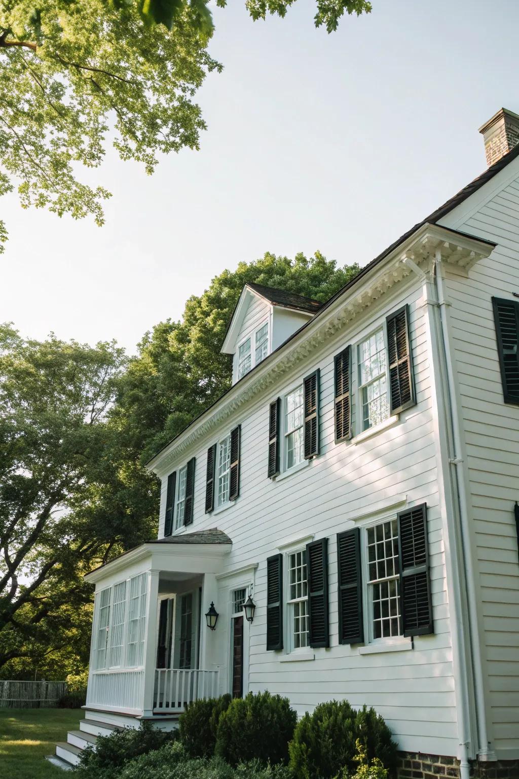 A traditional colonial residence showcasing a white exterior with striking black shutters.