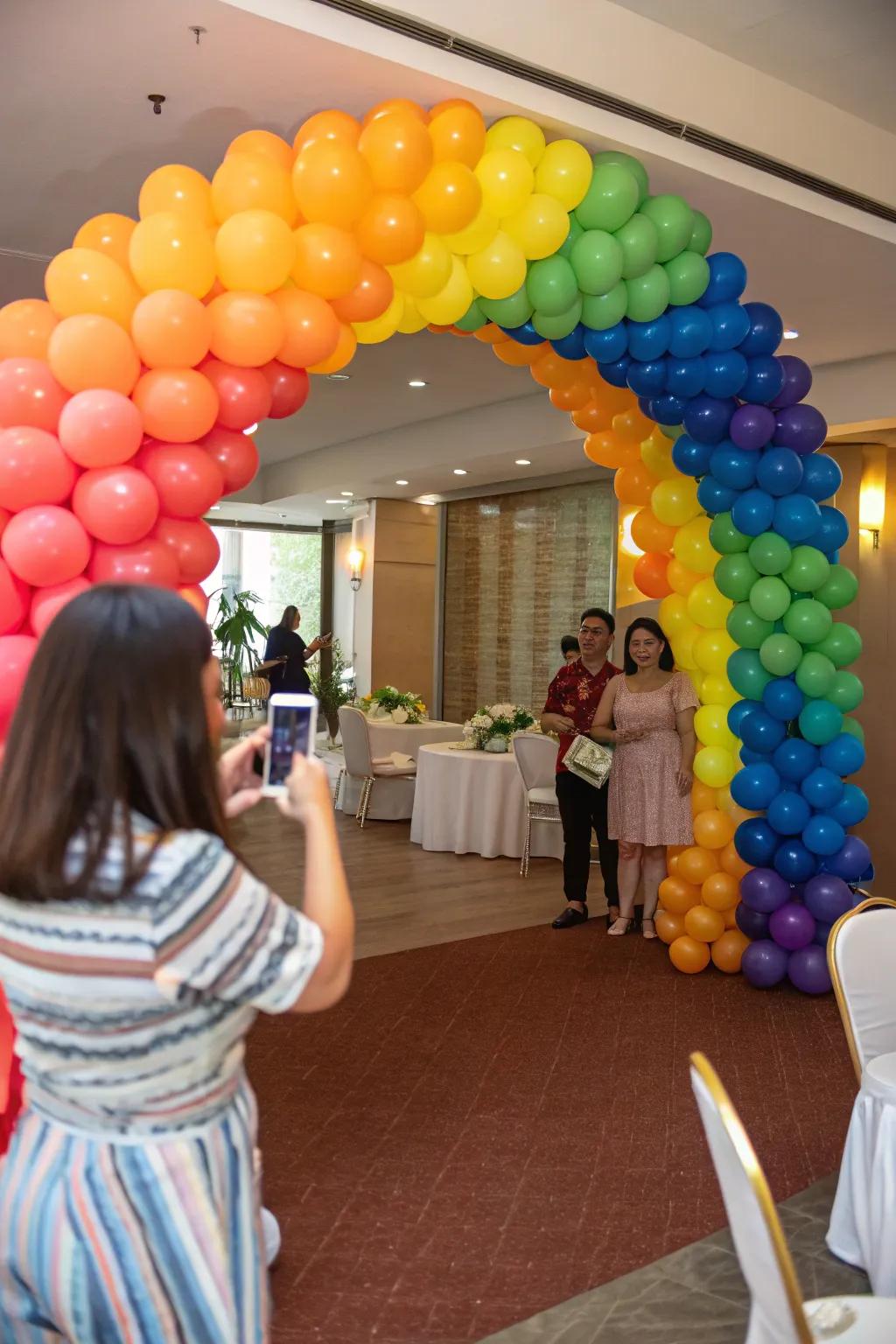 Attendees reveling beneath a vibrant spectrum balloon gateway at a party entrance.