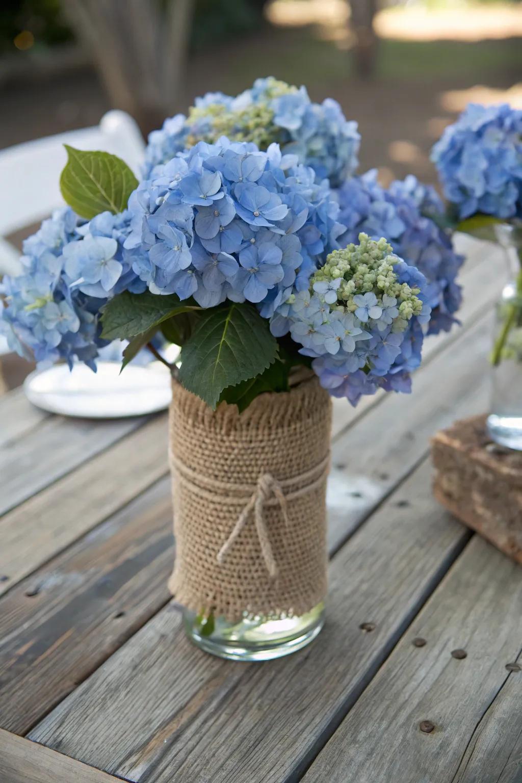 Burlap-wrapped vases add rustic elegance to blue hydrangeas.