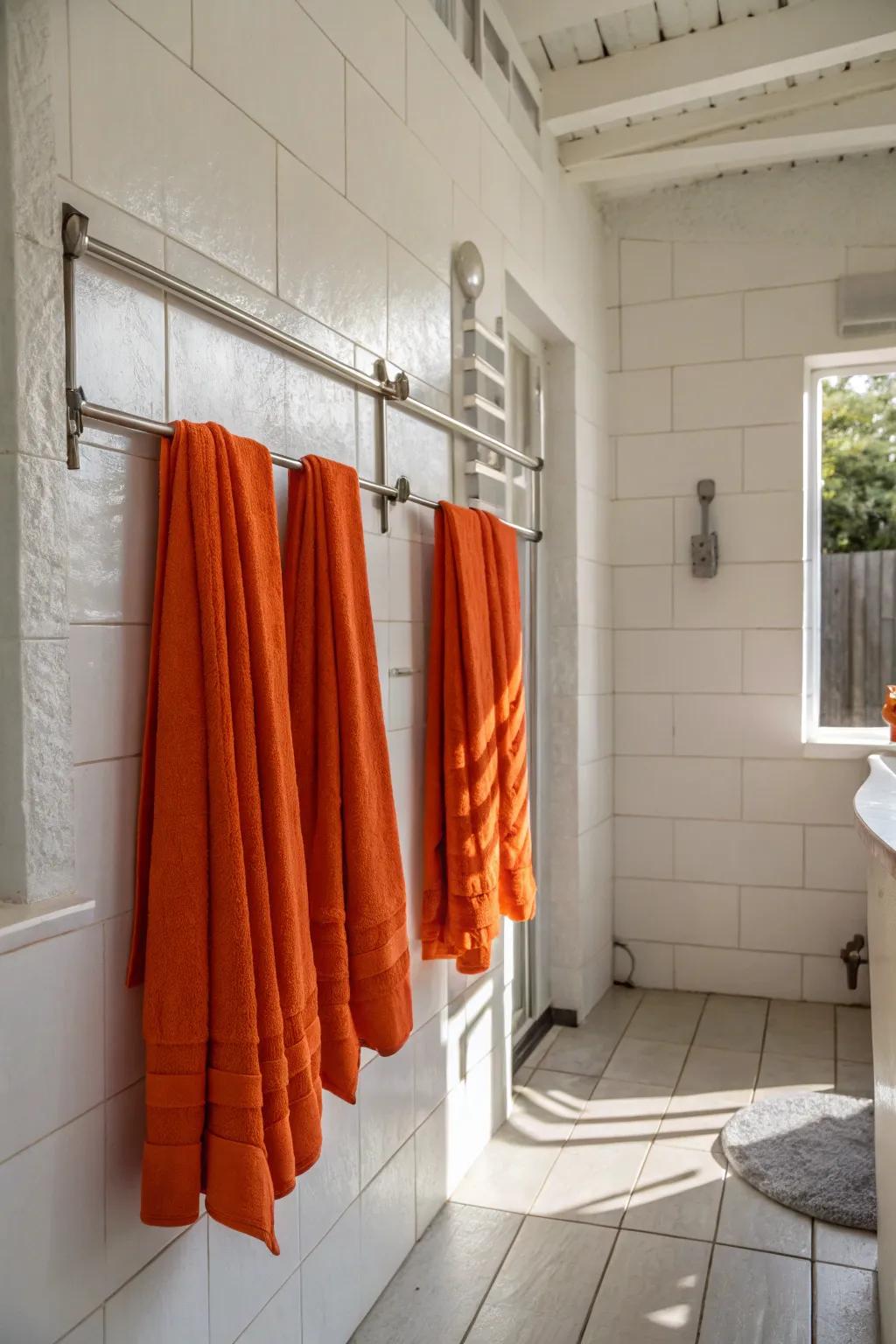 A pristine white bathroom enlivened with lively orange towels, introducing a pop of color.