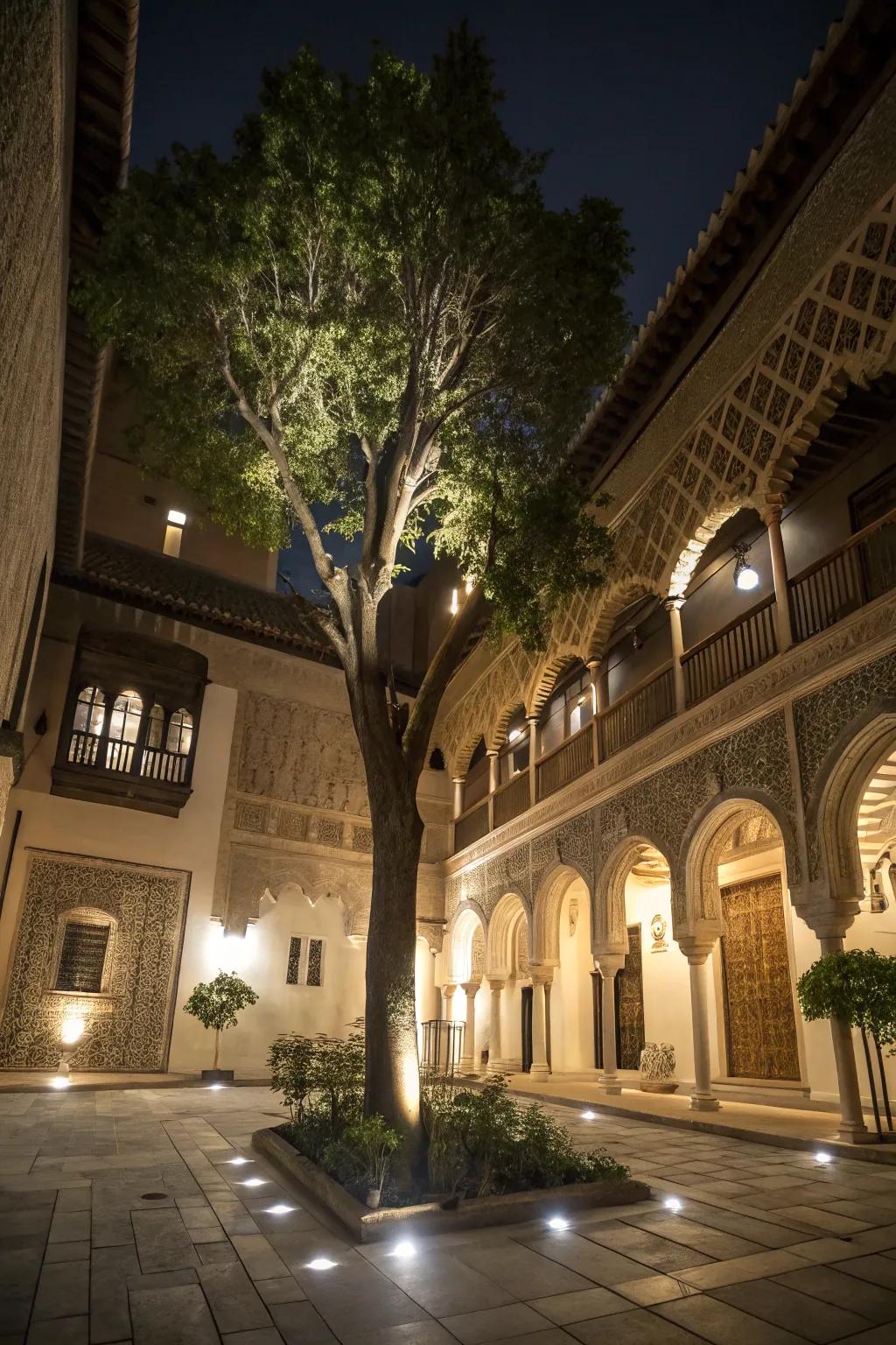 Spotlights accent the tree and architectural details within the courtyard.